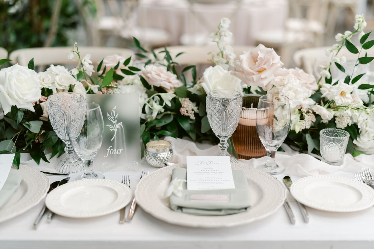 Table layout for wedding with white linens and pink rose centerpieces